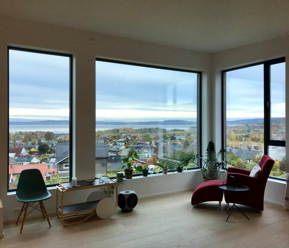 Stue med store vinduer og utsikt over byen og fjorden