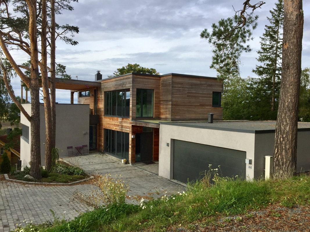 Moderne enebolig med flatt tak og garasje mellom furutrær