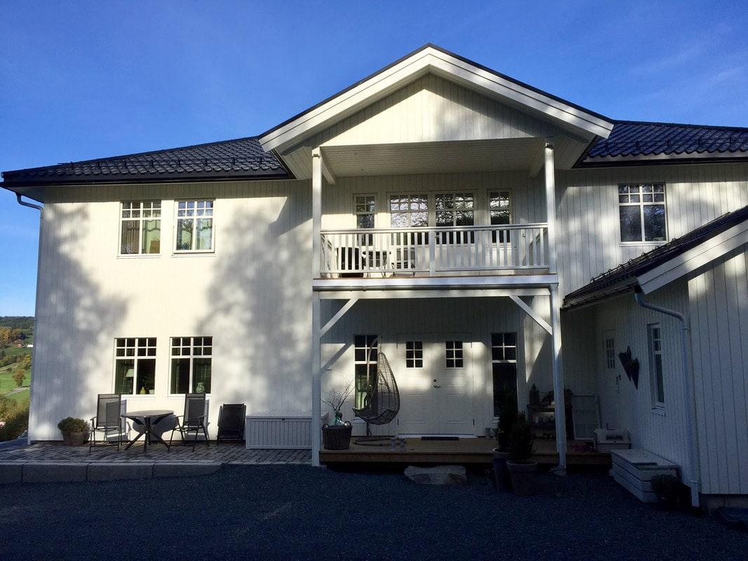 Hvitt tradisjonelt hus med balkong over inngangspartiet